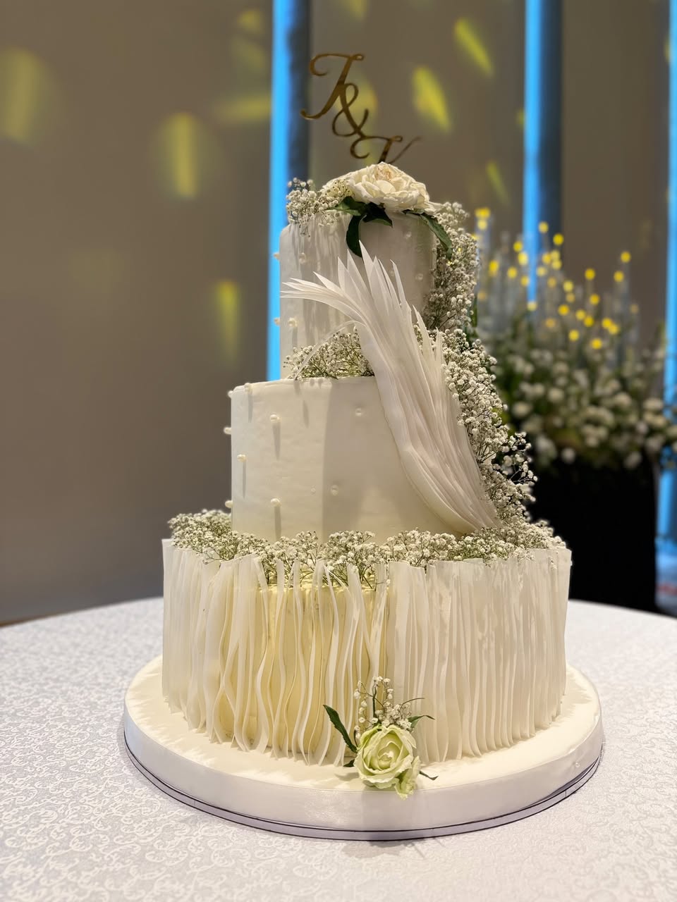 Three-tier ivory wedding cake with soft ruffles and delicate white flowers